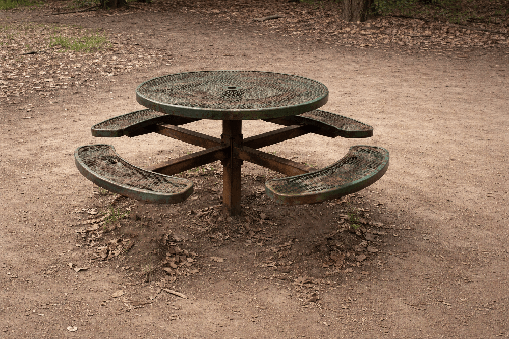 Worn and damaged inground picnic table showing long-term exposure effects in outdoor environments emphasizing durability considerations for commercial use